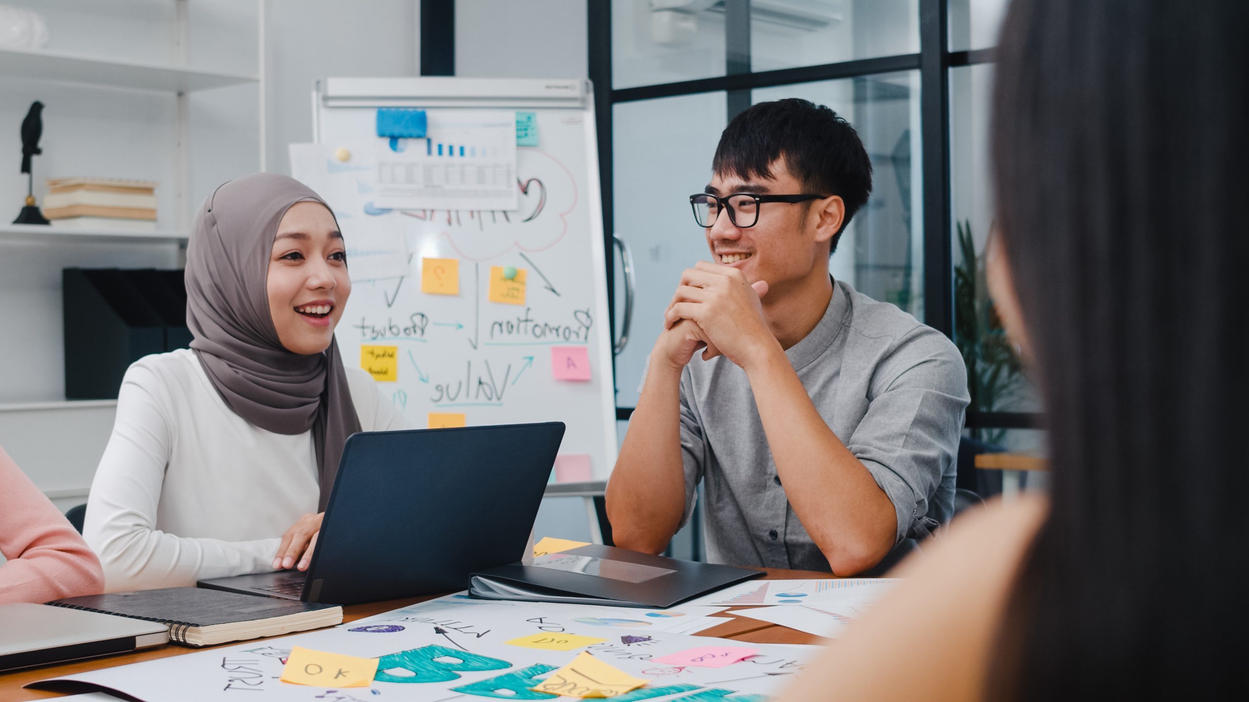 Multiracial group of young creative people in smart casual wear discussing business brainstorming meeting ideas mobile application software design project in modern office. Coworker teamwork concept.